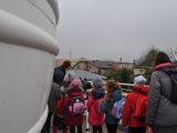 Grupa uczniów klasy trzeciej szkoły podstawowej i kobieta idą po okrągłym balkonie przy okrągłej, białej kopule.
