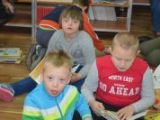 Troje dzieci ze szkoły podstawowej siedzi na podłodze i czytają książki.
