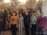 Grupa gimnazjalistw pozuje na zdjcia na tle grafiki w kolorach sepii przedstawicej rycerzy w zbrojach