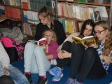 Cztery uczennice liceum siedzą na materacu na podłodze w bibliotece. Opierają się o siebie. Każda czyta książkę.