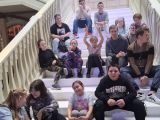 Grupa uśmiechniętych uczniów siedzi na białych schodach