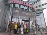 Grupa uczniów w kurtkach stoi na schodach przed wejściem do kina. Nad nimi duży, różowy napis Multikino