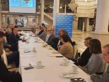 Grupa dorosłych siedzących przy stole konferencyjnym