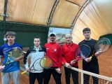 Trzech nastolatków i dwóch mężczyzn w sportowych ubraniach z rakietami do tenisa