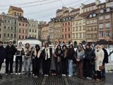 Grupa młodzieży na rynku miasta. W tle kamienice.