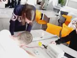 Czworo nastolatków przy stoliku wykonuje doświadczenia fizyczne