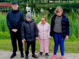 Dzieci stoją na tle łona natury. Z tyłu staw, zielone  sitowie.
