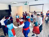 Osoby w strojach kujawskich tańczą w kółku.