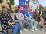 Czworo uczniów siedzących na krzesłach. Chłopak po lewej w czapce w kształcie głowy wilka
