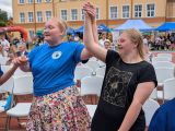 Dwie uśmiechnięte dziewczyny tańczą, trzymając się za ręce uniesione do góry