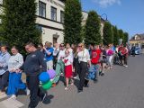 Grupa uczniów i nauczycieli maszeruje w barwnym korowodzie po ulicy miasta