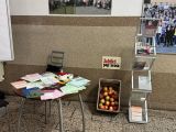 Stolik z ulotkami i skrzynka z jabłkami