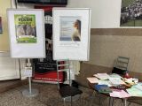 Dwa plakaty na stojakach obok stolik z ulotkami
