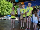 Trzej chłopcy w żółtych koszulkach na scenie. W tle inne dzieci,