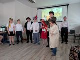 Grupa uczniów w przebraniach z bajek. W tle ekran z wyświetlanym kolorowym obrazem