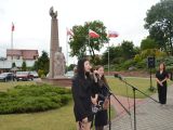 Na pierwszym planie dziewczynka śpiewa do mikrofonu. W tle pomnik Władysława Łokietka w otoczeniu biało-czerwonych flag.