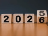 Na drewnianej podłodze z czterech kwadratowych drewnianych klocków ułożony napis 2025.