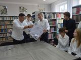 Dwóch licealistów i mężczyzna wysypują z urny kartki na stół. Po prawej stronie przy stole siedzią dwie dziewczyny, nad...