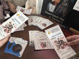 Ulotki leżą na stoliku. Na pierwszym planie ulotki trzmane w ręku.