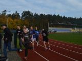 Siedmiu nastolatków w strojach sportowych wybiega przez bramę ze stadionu.