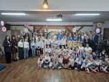 Duża grupa dzieci, młodzieży i dorosłych w auli szkolnej