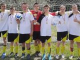Sześciu uczniów z medalami na szyjach, w biało-czarnych strojach sportowych. Między nimi uczeń w czerwonej koszulce...