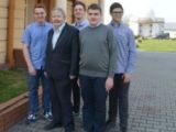 Przy wejściu do szkoły stoi w grupie czterech chłopców z gimnazjum i starszy mężczyzna z siwymi włosami.