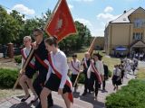 Duża grupa ludzi wchodzi po schodach do góry. W pierwszym i drugim rządzie młodzi ludzie niosą sztandar.