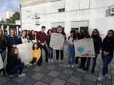 Grupa uczniów liceum stoi w rzędzie przed budynkiem. Trzy pary z grupy trzymają przed sobą duże papierowe plakaty.