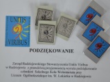 Biała kartka z tekstem podziękowania i logo "Unitis Viribus". U góry, na kartce leży sześć prostokątnych, metalowych odznak.