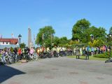 Grupa 50 osób stojących obok siebie z rowerami na dziedzińcu szkoły. Za nimi pomniek Władysława Łokietka.