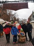 Czworo uczniów szkoły podstawowej stoi przy postaci św. Mikołaja przed wejściem na jarmark bozonarodzeniowy w Toruniu.