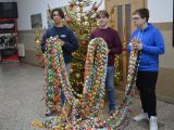 Trzech uczniów liceum stoi obok siebie. W rękach trzymają 100 metrów kolorowego łańcucha choinkowego.