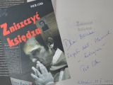 Okładka książki pt. "Zniszczyć księdza", po prawej stronie na białej kartce dedykacja autora książki i autograf.