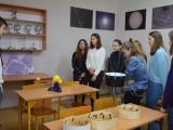 Siedmioro uczniów szkoły podstawowej stoi wokół stołu w sali lekcyjnej. Na stole model układu słonecznego.