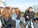 grupa uczniów szkoły podstawowej stoi na tarasie obserwatorium astronomicznego. Mężczyzna prezentuje im teleskop.