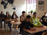 Uczniowie szkoły podstawowej siedzą w ławkach szkolnych w sali lekcyjnej.