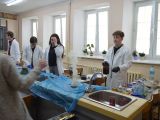 Czworo uczniów luceum stoi przy długim stole laboratoryjnym i wykonuje doświadczenia chemiczne.
