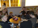 Dwunastu uczniw liceum siedzi przy stolikach w auli szkolenj, rozmawiaj i jedz.