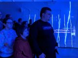 Grupa gimnazialistów w sali z przyciemnionym niebieskim światłem