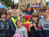 Grupa uczniów z pomalowanymi kolorowo twarzami. W tle kobieta w okularach