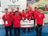 Grupa gimnazjalistów w czerwonych koszulkach z medalami na piersi.