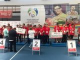 Grupa młodych sportowców w czerwonych strojach. W tle napis XII Ogólnopolskie Igrzyska Olimpiad Spoecjalnych