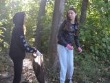 Dwie licealistki stoją między drzewami w lesie. Jedna trzyma foliowy worek.