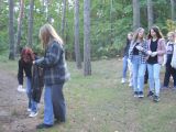 Grupa licealistów spaceruje po lesie i zbiera śmieci do foliowego worka.