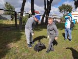 Trzech uczniów zbierających śmieci. Między nimi szary foliowyn worek