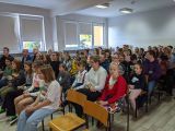 Duża siedząca na krzesłach grupa uczniów