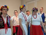 Trzy śpiewające gimnazjalistki w strojach ludowych z czerwonymi koralami i wiankami na głowie
