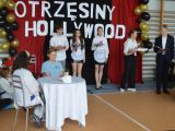 Przy stoliku przykrytym białym obrusem siedzą dwie uczennice liceum. Przy ścianie stoją dwie dziewczyny i chłopak, wszyscy...