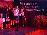 Na scenie w rzędzie stoi grupa uczniów liceum, chłopcy i dziewczyny. Na scęną pada czerwone światło. Pośrodku sceny...